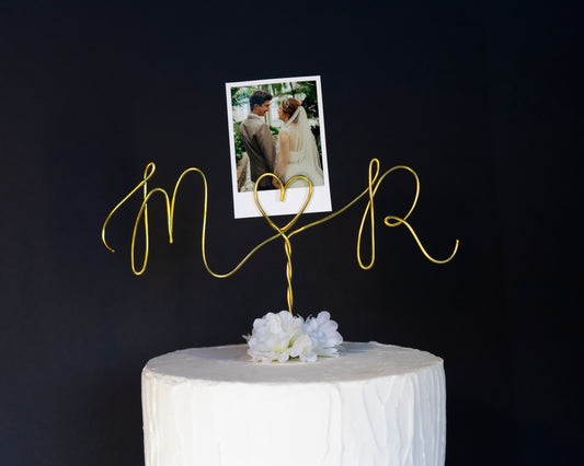 Decorative gold cake topper with initials letters and a photo of a couple on a black background